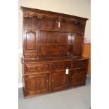 An oak dresser, the upper section fitted two open shelves, two cupboards and two drawers, over three