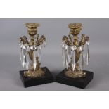 A pair of early 19th century gilt bronze dolphin and cut glass table lustre candlesticks, on black