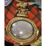 A circular giltwood wall mirror with eagle finial and carved balls flanked by candleholders (now