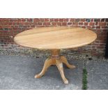 A light oak circular dining table, by Richard A Gibson, on turned column and quadruple splay