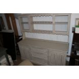 A cream painted oak dresser, the upper section with galleried shelves and cupboards enclosed wire