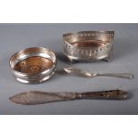 A silver wine bottle coaster, an oval silver cruet stand with pierced decoration, a silver butter