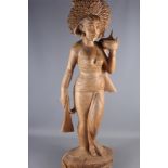 An Indonesian carved wooden figure of a female standing on a lotus flower, 41" high