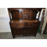 An Ercol style dark oak court cupboard with central cupboard over two drawers and cupboards, on