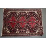 A Qashqai rug with three red medallions on a dark floral ground, 60" x 42" approx