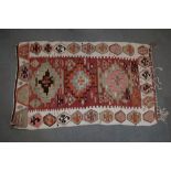 A kelim rug with three medallions on a salmon ground and single border in shades of red brown and