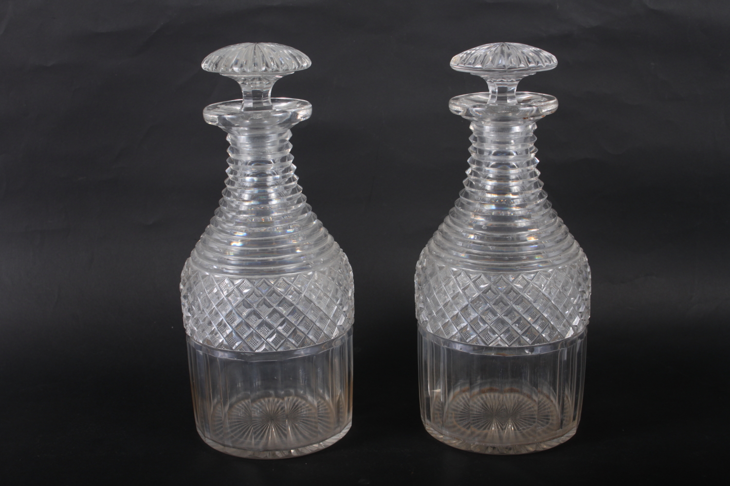 A pair of Georgian cut glass decanters with ribbed necks, 10 1/4" high (chips to stoppers and necks)