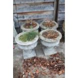 A set of four cast stone planters, on square bases, 15 1/2" dia x 16 1/2" high