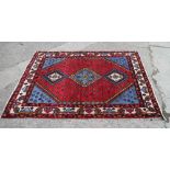 A Persian woven village rug of traditional design on a red ground, 78" x 59" approx