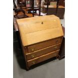 A light oak fall front bureau with fitted interior over three long drawers, on cabriole supports,