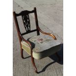 An Edwardian carved walnut low seat nursing chair, upholstered in a cut velour, on splay castored