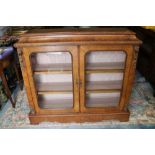 A Victorian figured walnut gilt metal mounted low bookcase enclosed two glazed arch top doors, on