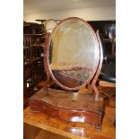 A George III mahogany, box and ebony strung serpentine front oval swing frame toilet mirror, on