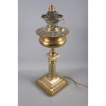 A brass oil lamp with embossed decoration, on a square base, 21" high (now converted to electricity)
