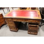 An Edwardian oak double pedestal desk with red leather lined top, fitted nine drawers, on block