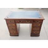 An Edwardian walnut double pedestal desk with tooled lined top fitted nine drawers, on block base,
