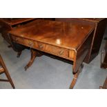 A mahogany drop flap sofa table, fitted two drawers, on splayed and castored supports, 35" wide x