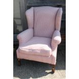 A wing armchair, upholstered in a red check, on cabriole claw and ball supports