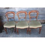 A set of four Victorian carved walnut loop back side chairs, on shaped supports