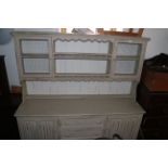 A cream painted oak dresser, the upper section with galleried shelves and cupboards enclosed wire