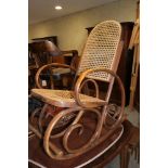 A polished as walnut bentwood rocking chair with cane seat and back panels (seat for repair)
