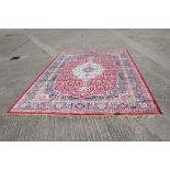 A Kashmir full pile carpet with traditional central medallion design and multi-borders on a red