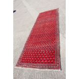 A Persian runner with acorn design and multi-borders on a red ground, 115" x 42 1/2" approx