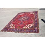 A vintage Persian Tabriz rug with central floral medallion design on a red ground with multi-