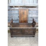 A monk's carved oak bench with box seat and lion arms, 42 1/2" wide x 18" deep x 29 1/2" high