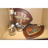 Two painted metal coats of arms on easel stands, 12 1/2" high, a brass chamberstick (now converted