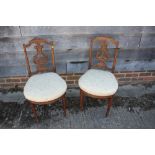 A pair of Edwardian carved walnut salon chairs with lyre backs and stuffed over seats, on fluted