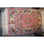 A pair of Chinese contour pile rugs with floral design on a pink ground, 38" x 24" approx