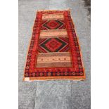 A flat weave and pile rug with three panels on an orange ground, 77" x 37" approx