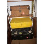 A black metal uniform trunk, 35" wide, and two other metal trunks, one painted yellow