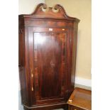 A George III crossbanded mahogany corner cabinet on stand with plain crossbanded door enclosing
