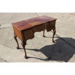 A Georgian design walnut serpentine front dressing/writing table, fitted three drawers, on carved