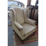 An early 20th century wing armchair, upholstered in a gold velour, on cabriole supports