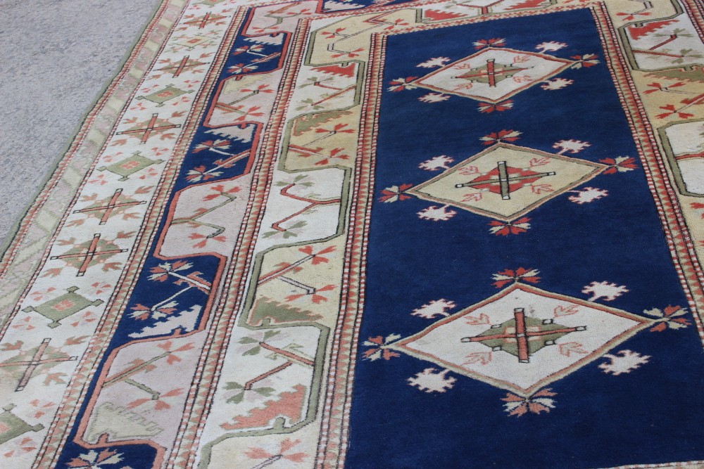 A Caucasian wool pile carpet with central guls and geometric and floral designs, on a terracotta - Image 3 of 6