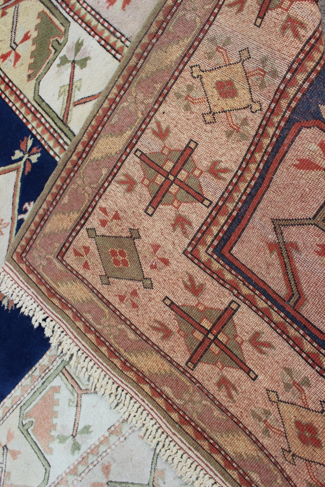 A Caucasian wool pile carpet with central guls and geometric and floral designs, on a terracotta - Image 5 of 6