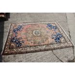 A Persian rug with central medallion, floral designs and multi-guard borders on a terracotta ground,