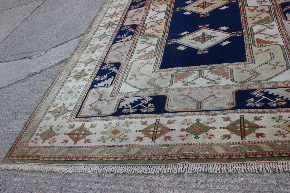 A Caucasian wool pile carpet with central guls and geometric and floral designs, on a terracotta - Image 2 of 6