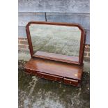 A mahogany swing frame toilet mirror, on plateau base, fitted three drawers on ogee bracket feet,