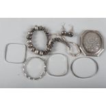 Four silver bangles, a white metal necklace and earrings and an embossed white metal powder compact