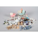 A collection of dolls house china, two early plastic prams, a 1930s Parisian model of a chair with a