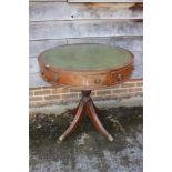 A mahogany drum table with tooled lined gilt green leather top, fitted three drawers, on turned