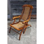 A 19th century walnut folding armchair with caned seat and back