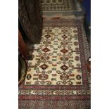 A Kuba design tribal rug with serpent scrolls on a cream ground and multi-bordered in shades of