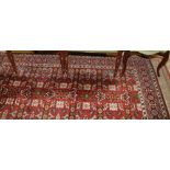 A wool rug of traditional design on a red ground and multi-bordered in shades of red, green, blue