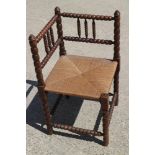 An early 20th century bobbin turned corner elbow chair with rush envelope seat