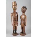 Two East African carved hardwood figures, he in military uniform, she naked, largest 27 1/2" high